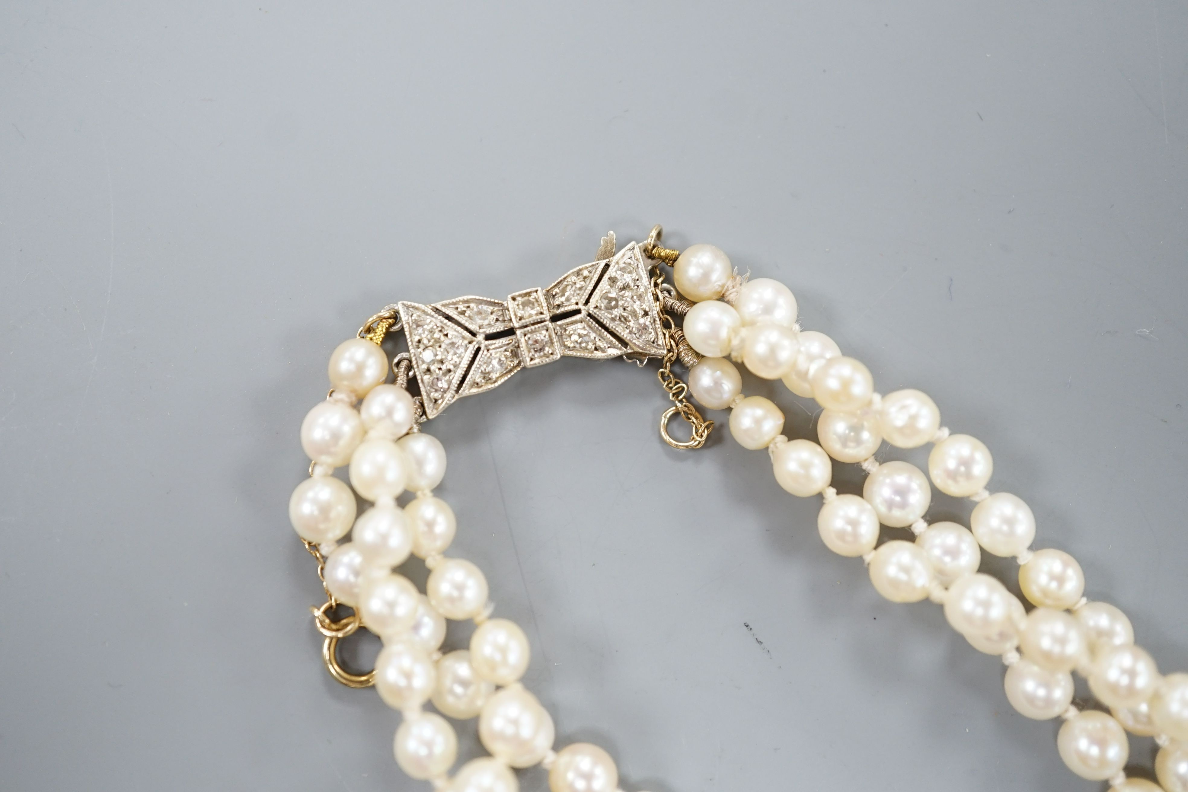 A modern triple strand graduated cultured pearl choker necklace, with diamond chip set white metal clasp, 38cm.